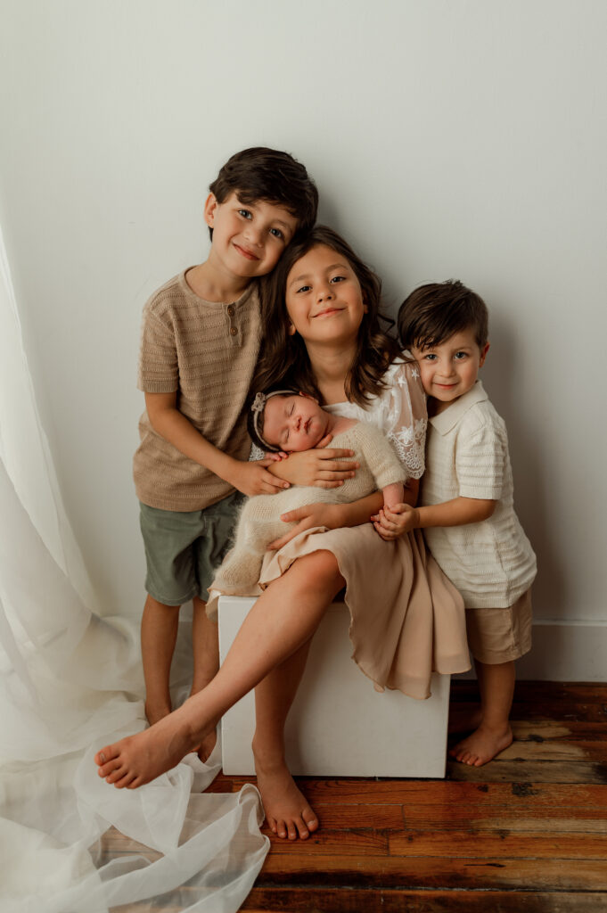 picture of 2 brothers and an older sister and baby sister posed in a studio setting