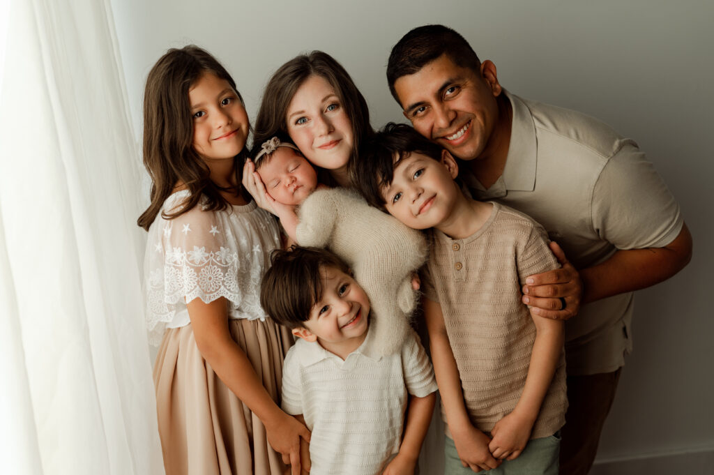 family photo of 6 in a studio session with youngest being a newborn
