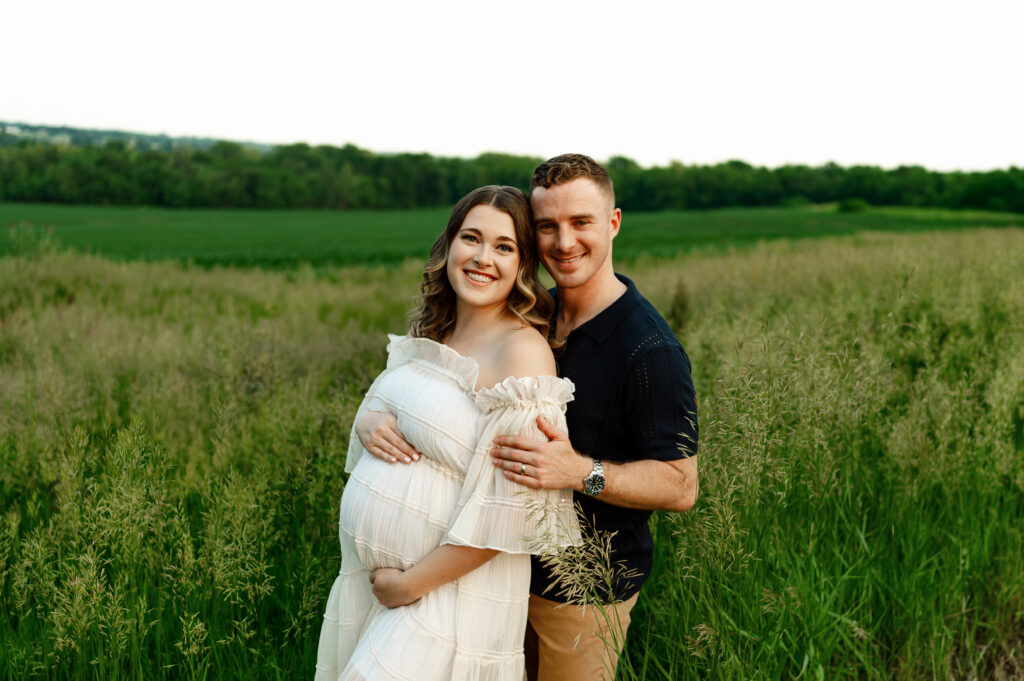 couple posed for maternity photos in a field