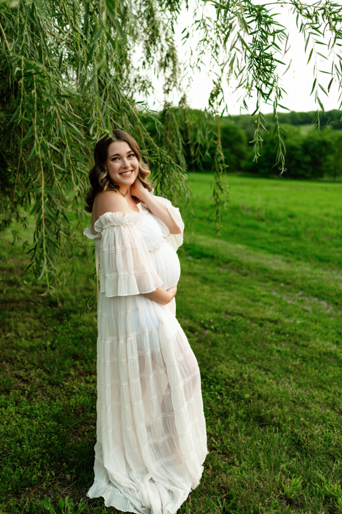 a pregnant mother posed under a willow tree