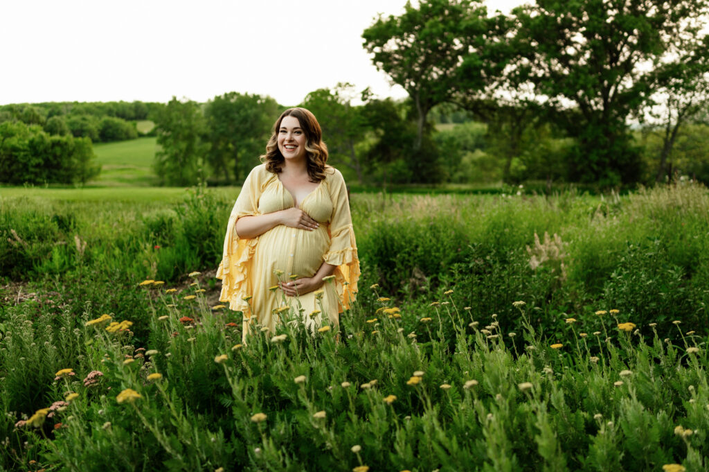 yellow flowers and a pregnant women posed in a yellow dress