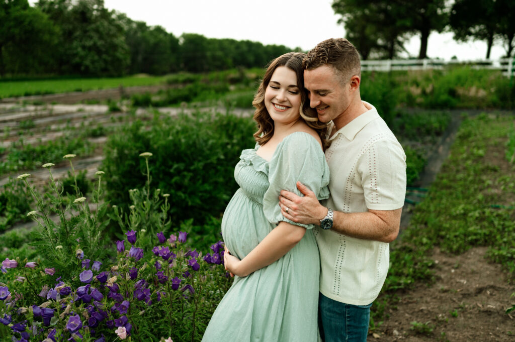couple posed near purple flowers for materntiy photos